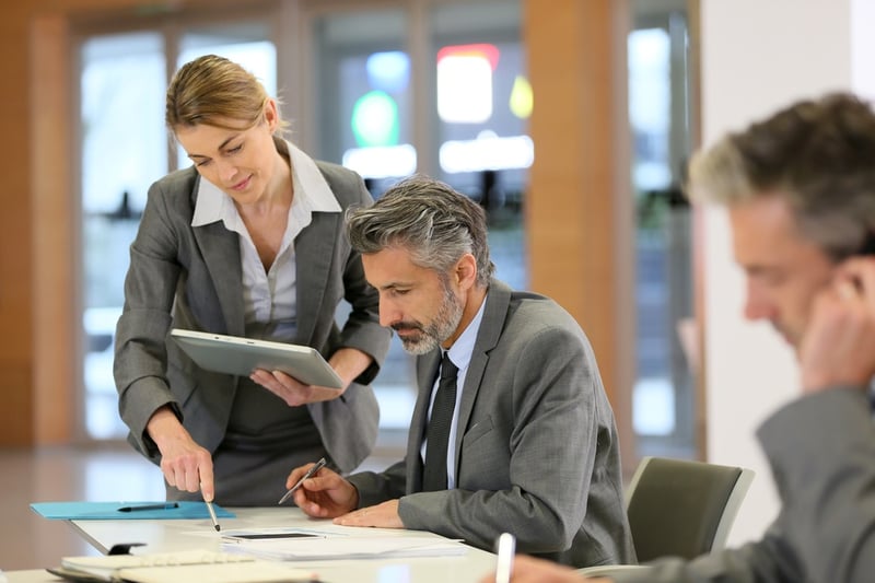 A woman and man in suits reviewing a document together.